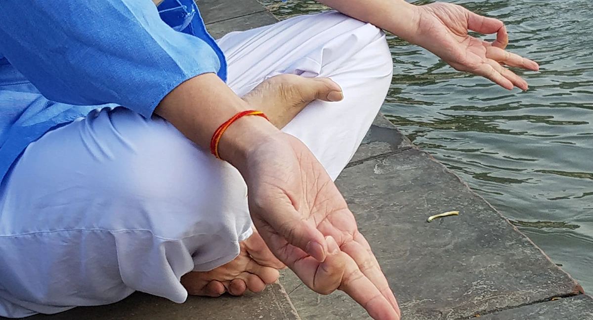 A student performing bandha Mudra Asana on the bank of river Ganga