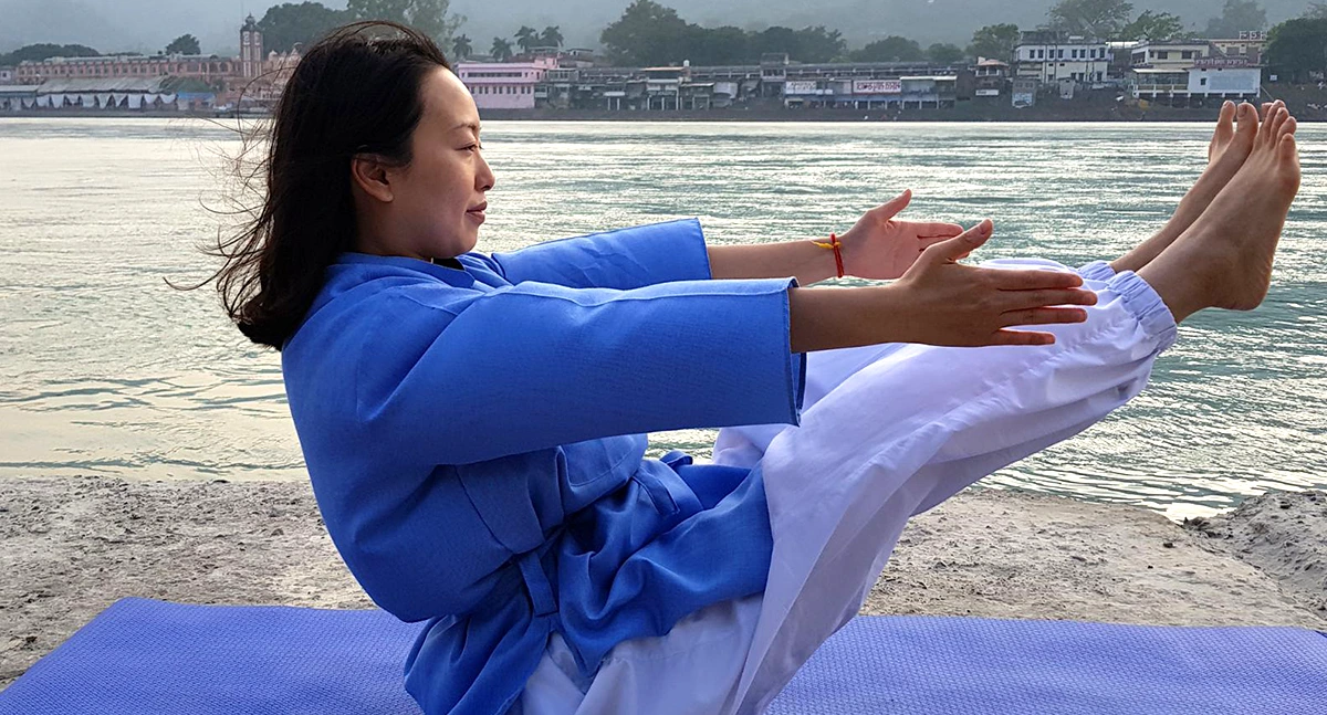A student performing Hatha Yoga Asana on the bank of river Ganga